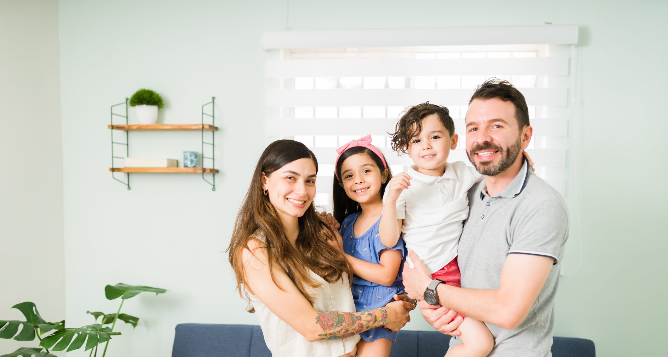 Portrait of a beautiful family of four with adorable little children smiling and making eye contact while spending a relaxing day together at home